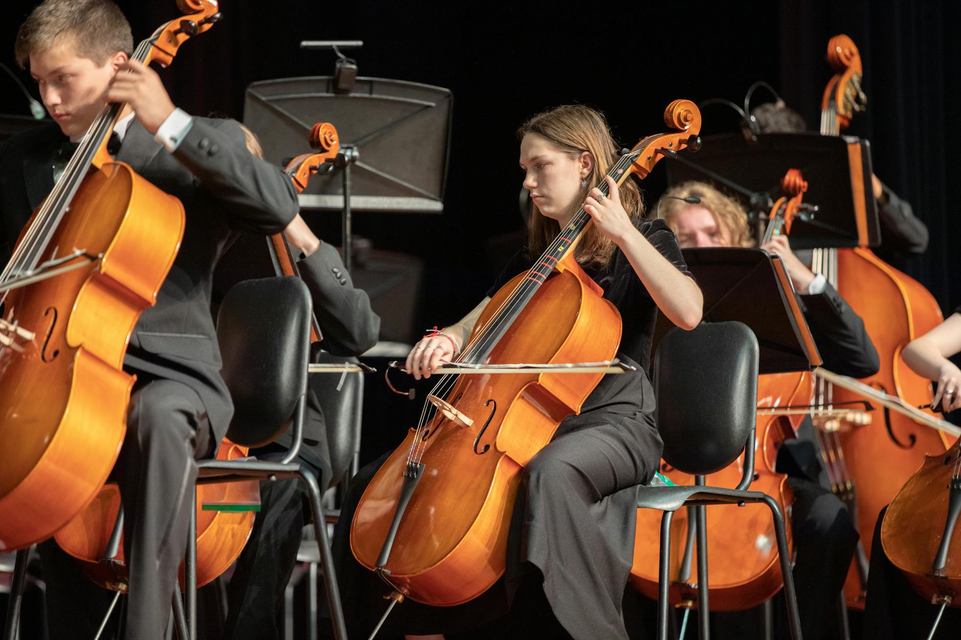 Orchestra cellists performing classical music in an indoor concert setting.