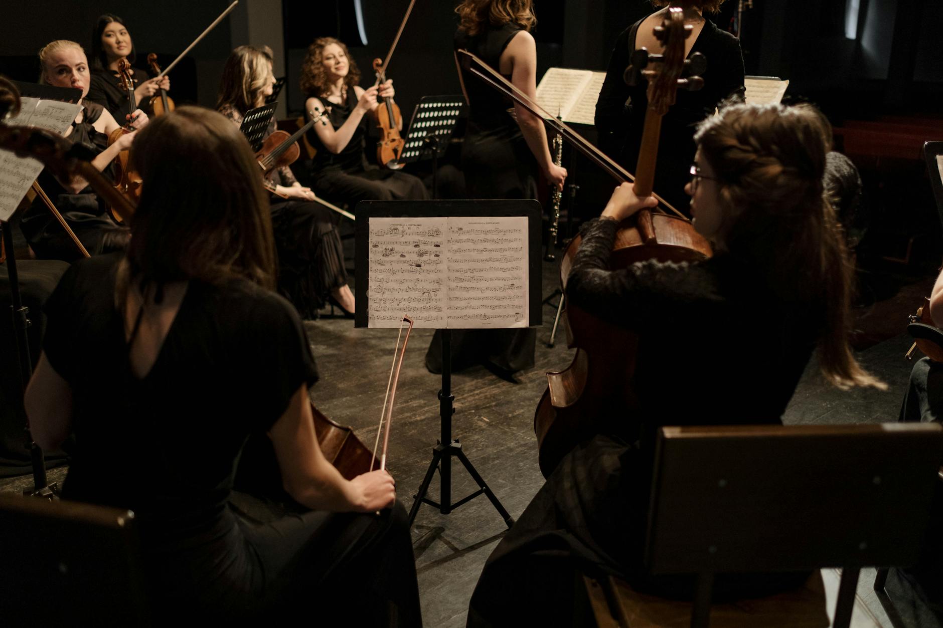 Group of musicians playing classical music with violins and cellos on stage in a concert.