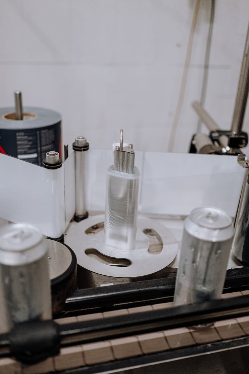 Close-up of an automated system labeling beverage cans in a modern brewery factory.