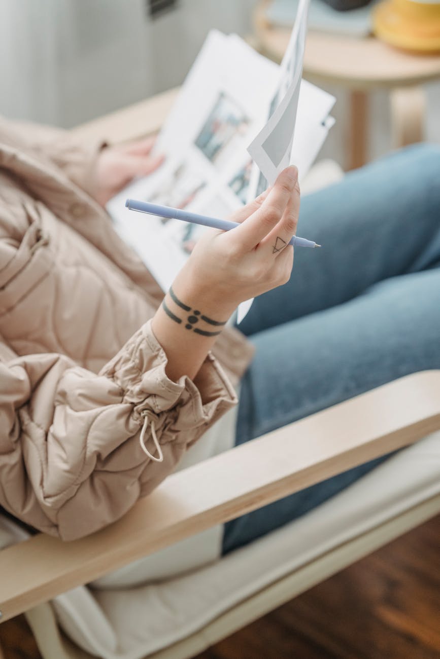 A designer sitting indoors reviewing project sheets with a pen in hand, showcasing creativity and focus.