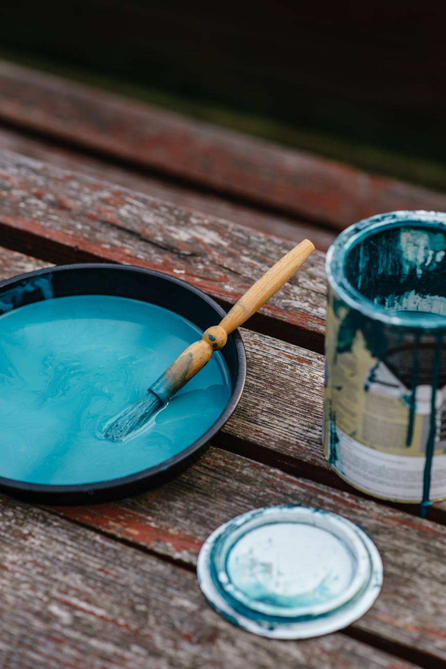 Turquoise paint with a brush on a rustic wooden surface, perfect for creative projects.