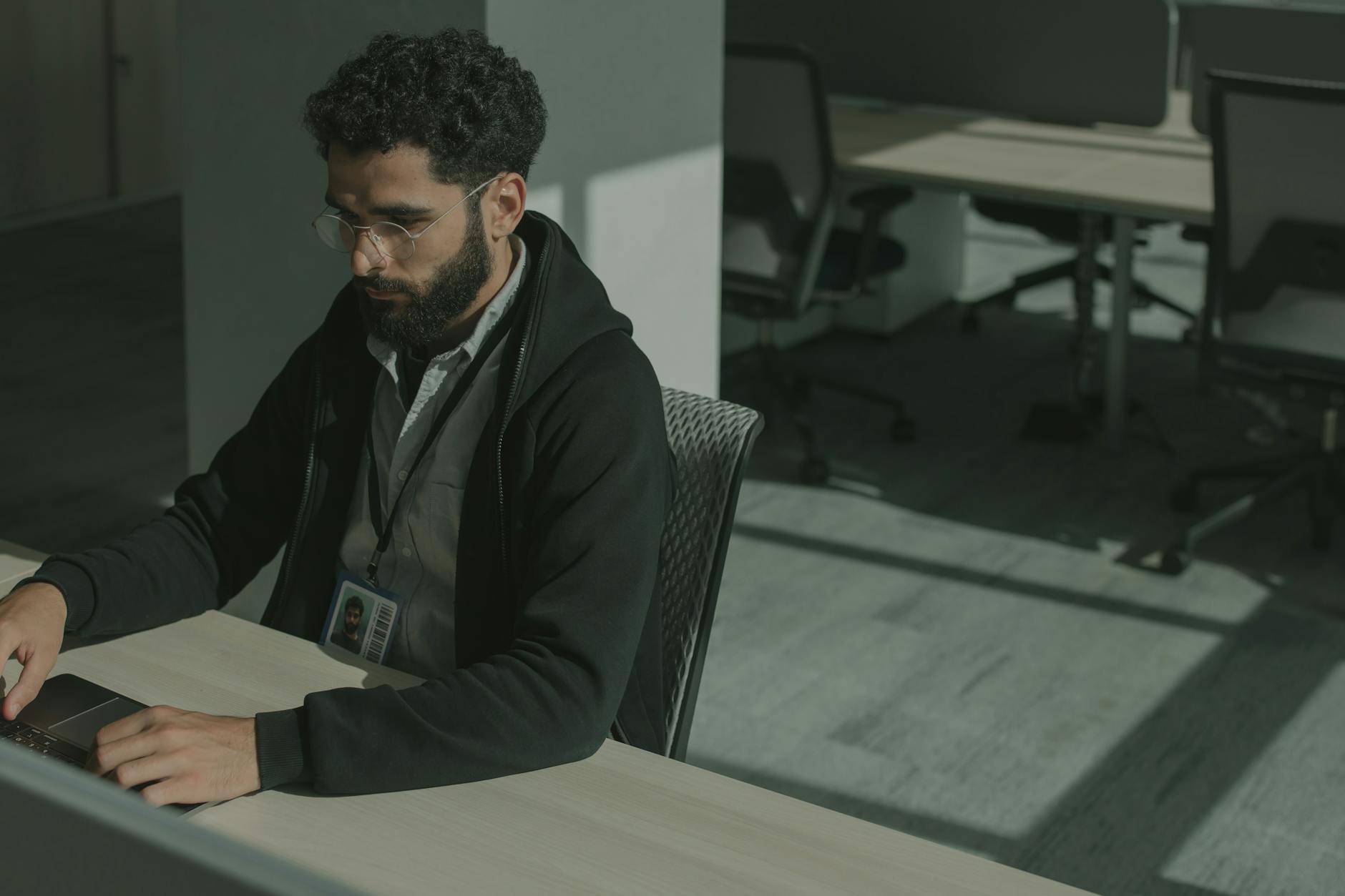 Bearded man working on a computer indoors, focused on cybersecurity tasks.