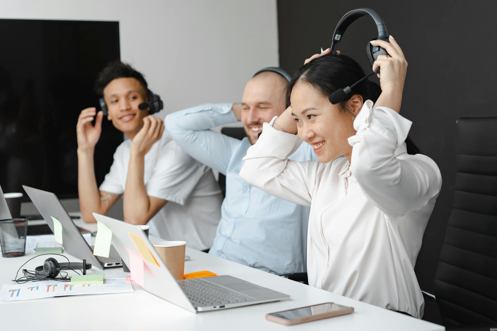 Group of diverse coworkers collaborating in a call center setting, wearing headsets and working together.