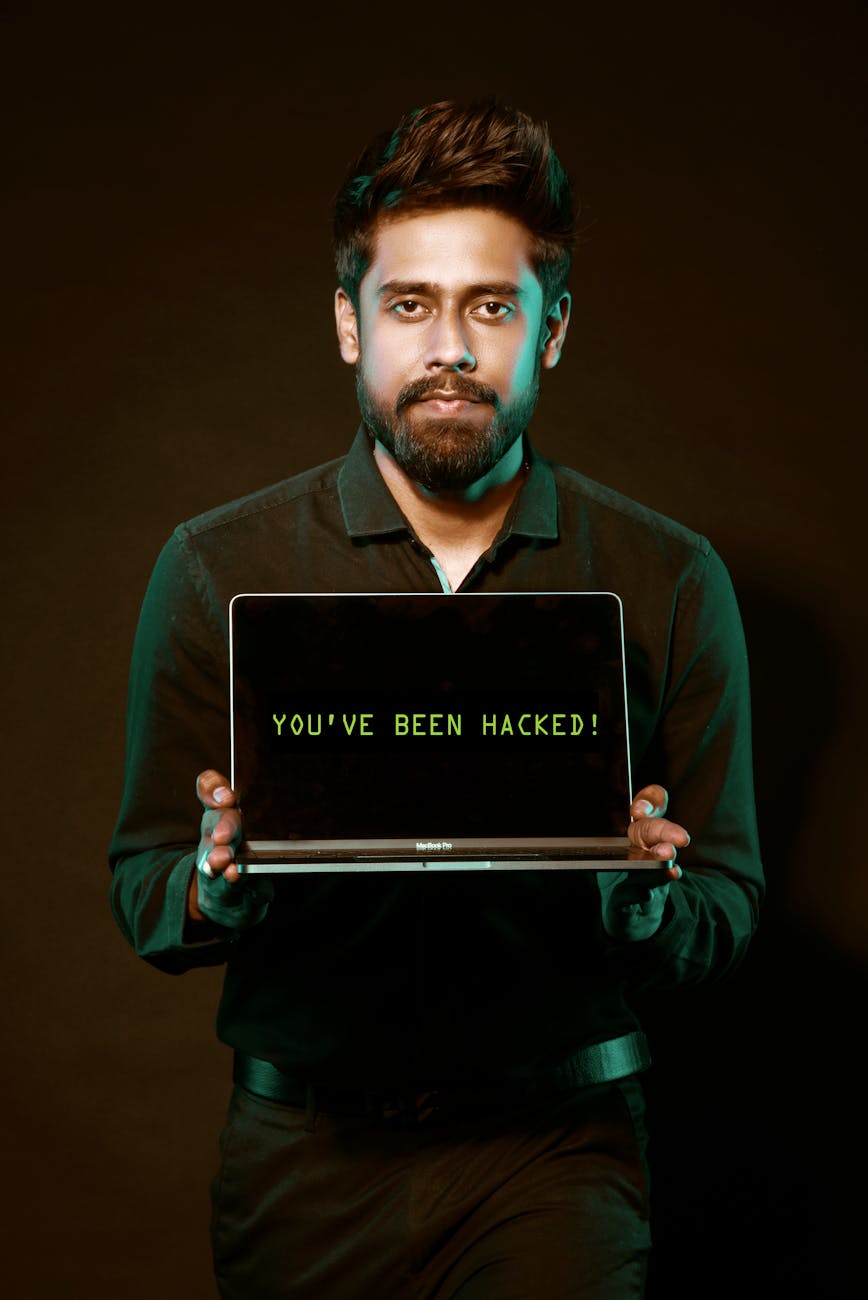 A man showing a laptop with a 'You've been hacked' message, symbolizing cyber security threats.