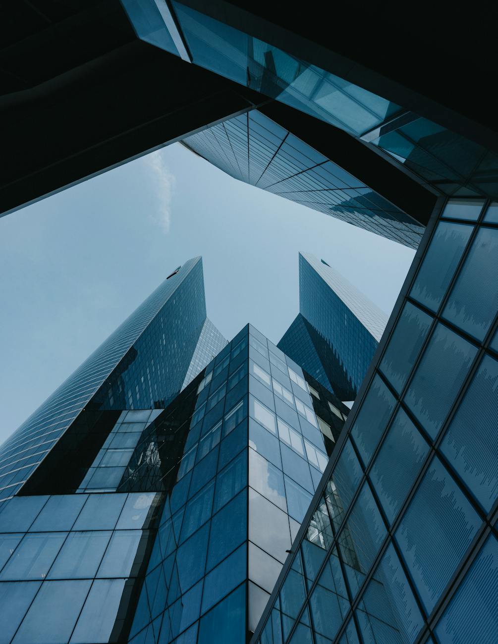 Low angle view of futuristic skyscrapers with glass facades against a clear blue sky.