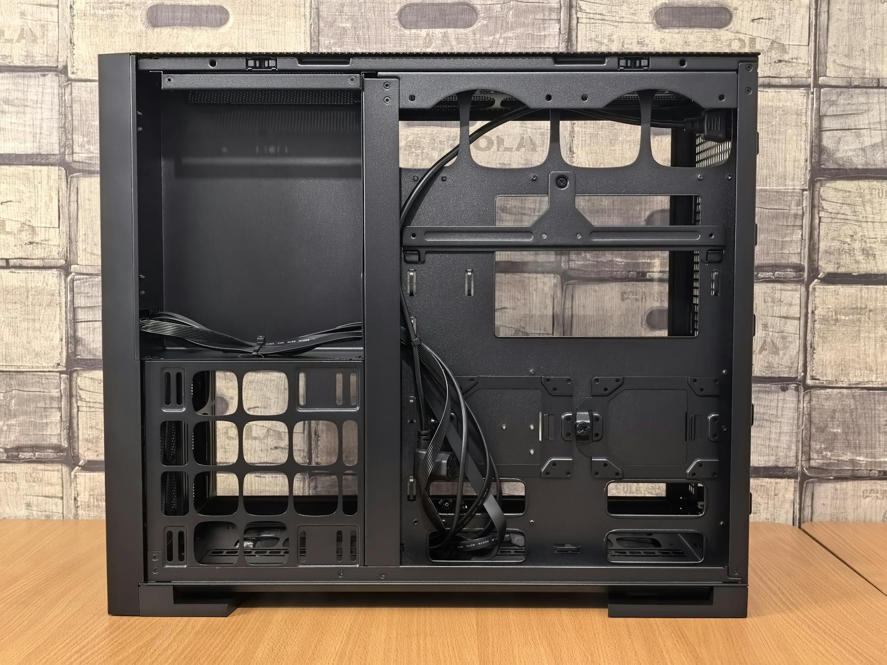 An open black computer case ready for PC assembly, placed on a wooden table.