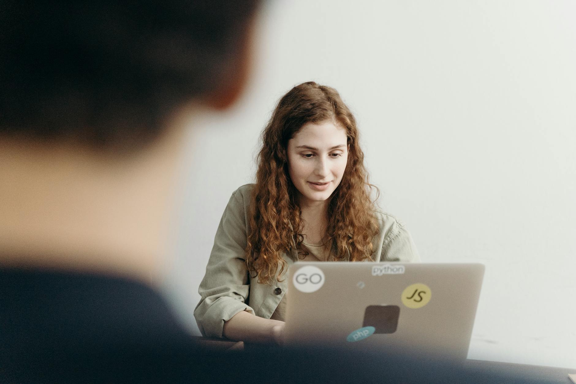 Young professional woman working on a laptop in an office setting, concentrating on her task.
