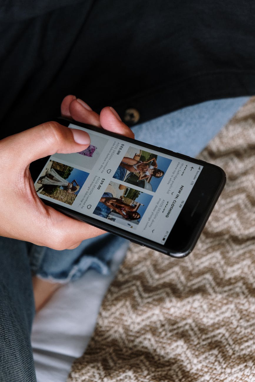 Close-up of a person browsing a fashion app on a smartphone indoors.