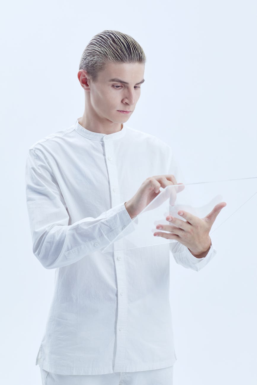 Man in white interacts with transparent tech panel in modern studio setting.