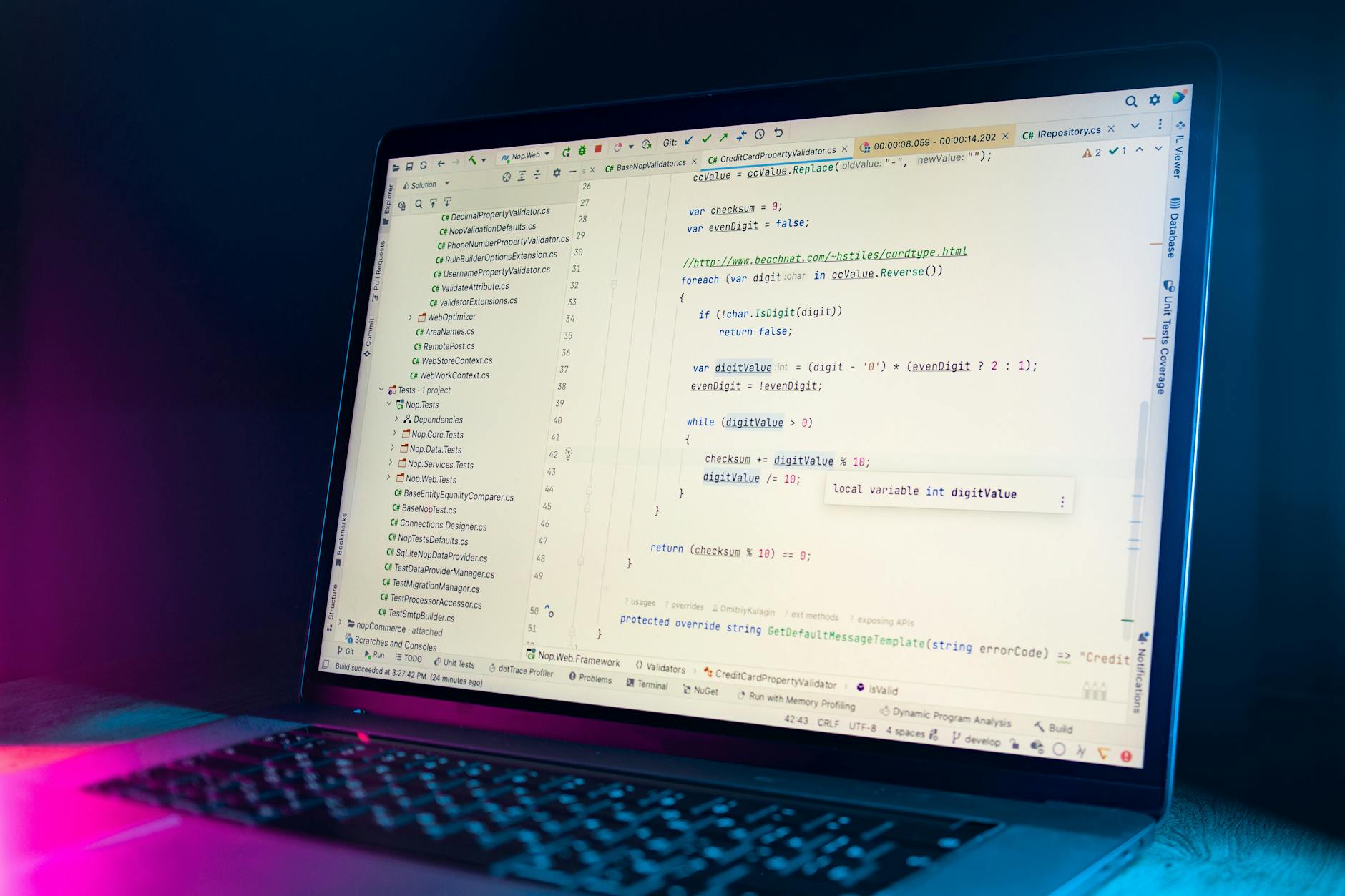 A laptop screen showing a code editor with visible programming code in a dimly lit environment.