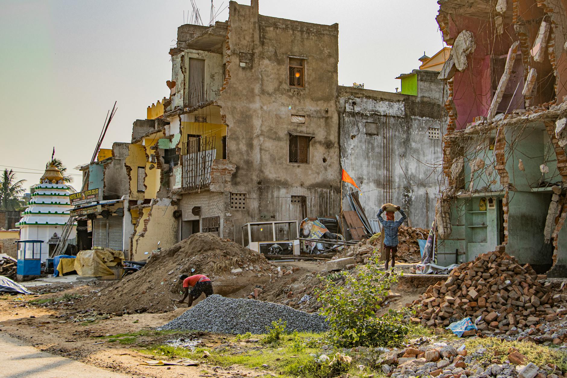 A detailed view of urban decay and reconstruction efforts in Puri, India, showcasing damaged buildings and workers.