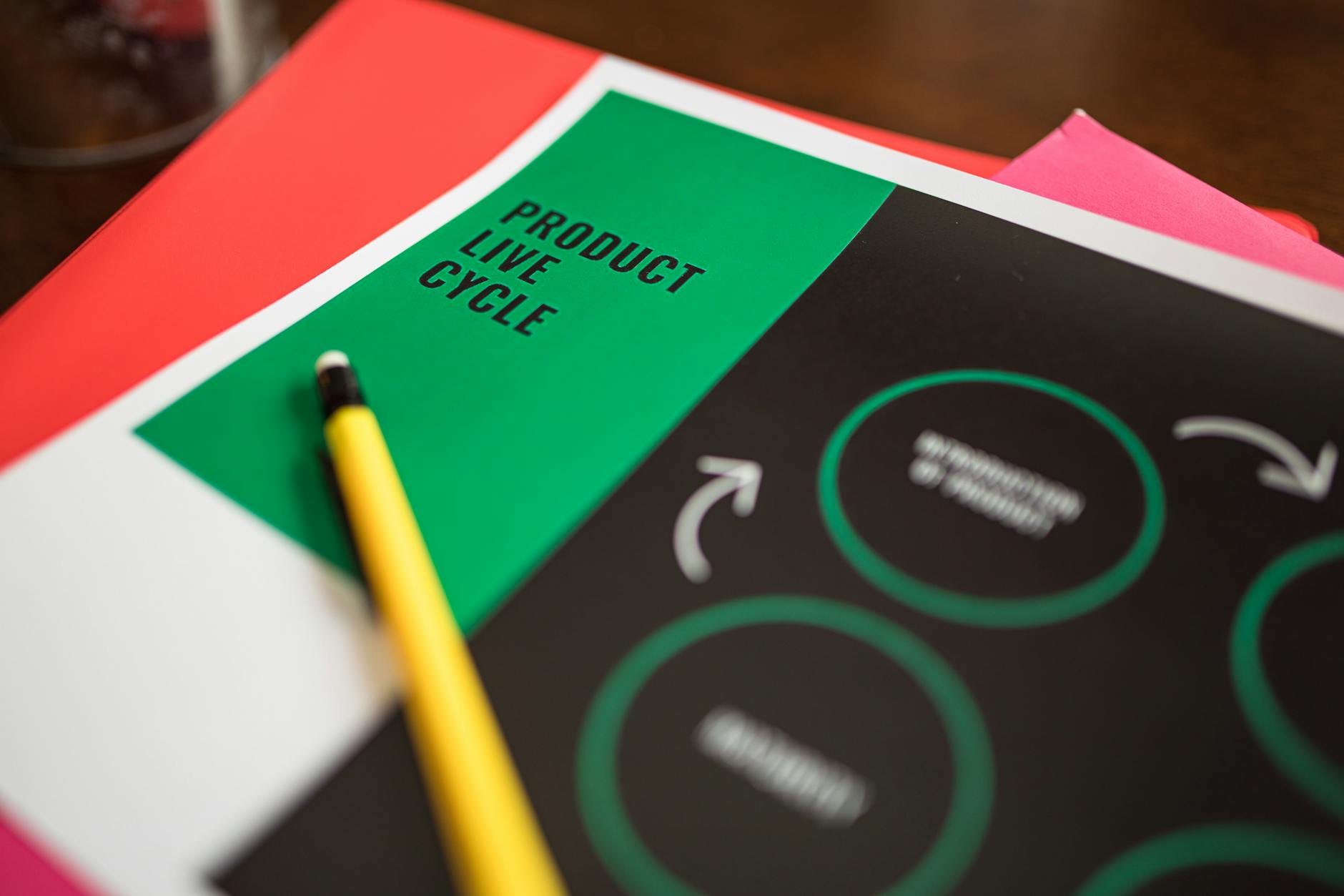 Close-up of a product life cycle diagram with colorful papers and a pencil.