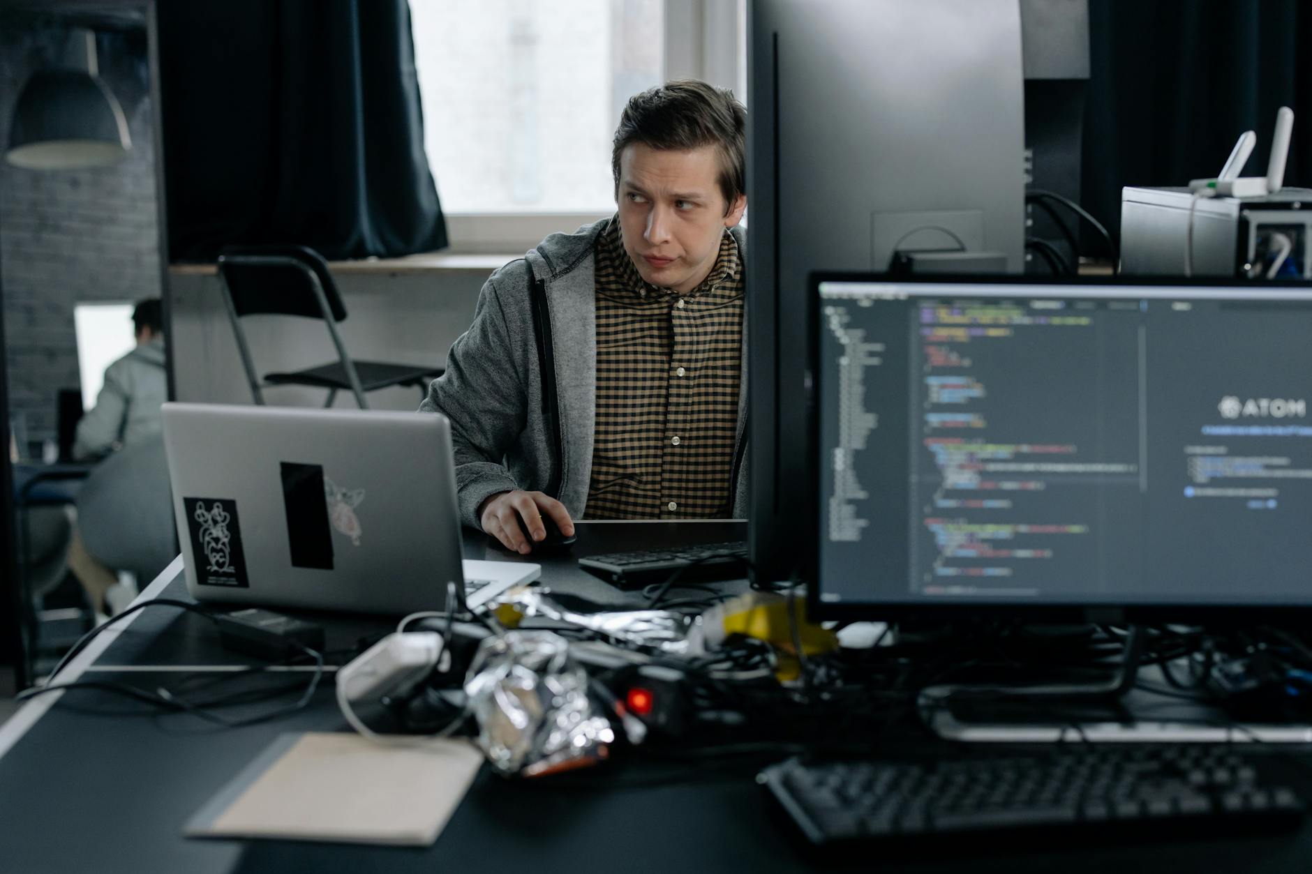A programmer in a modern office working on computer code, showcasing a focused work environment.