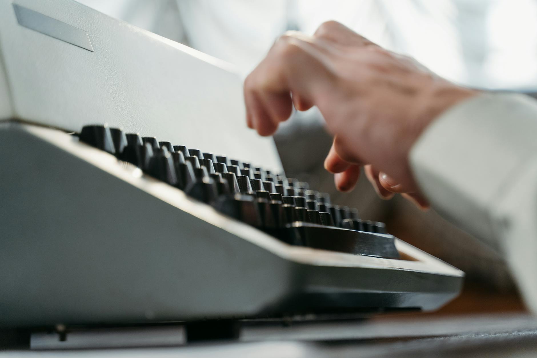 Detailed shot of hands typing on an antique typewriter, showcasing vintage technology.