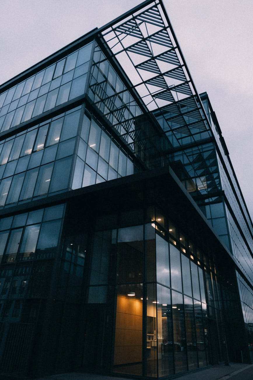 A sleek and modern glass building featuring contemporary architectural elements under a cloudy sky.