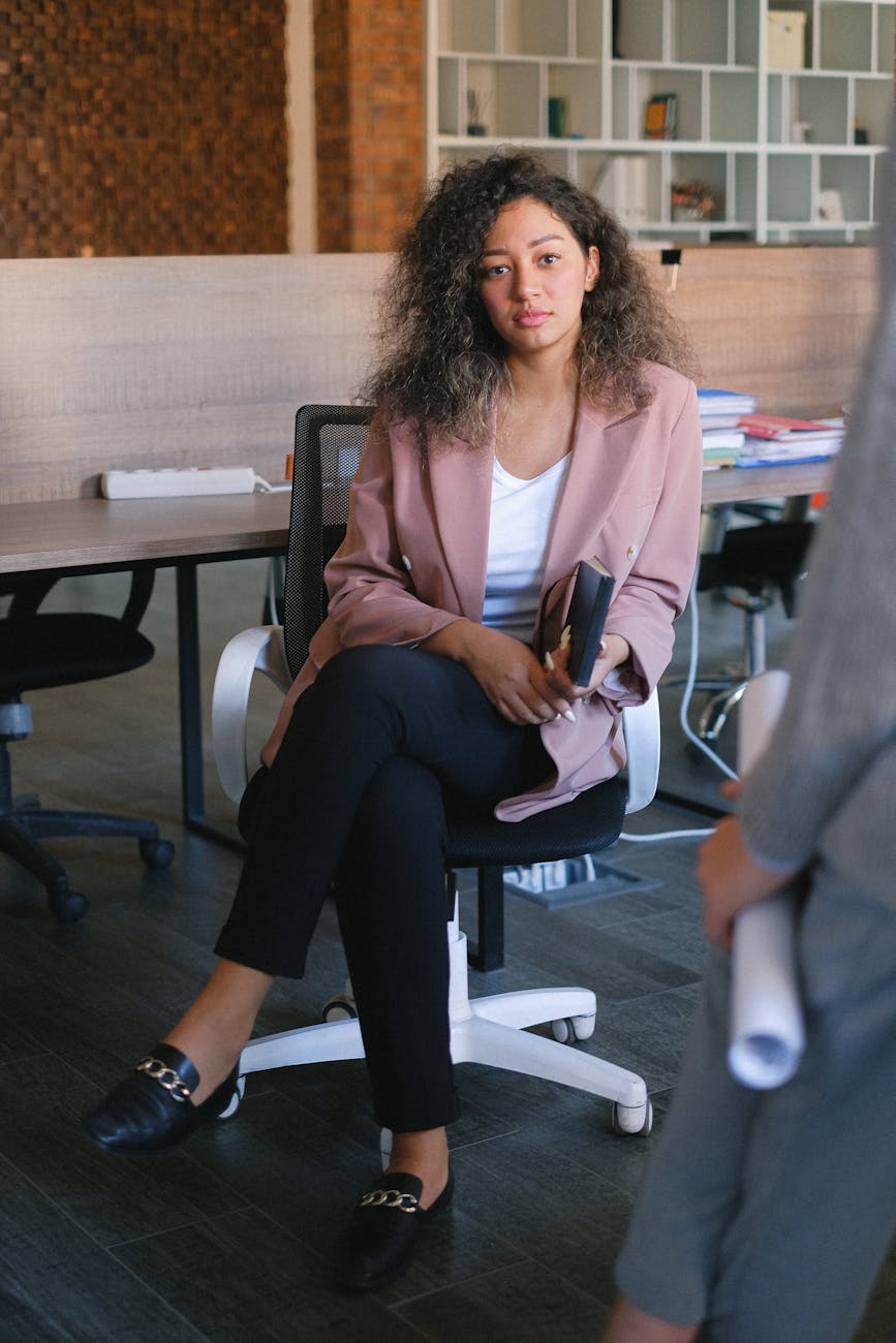 Full body of female manager listening to coworker report during business discussion in office
