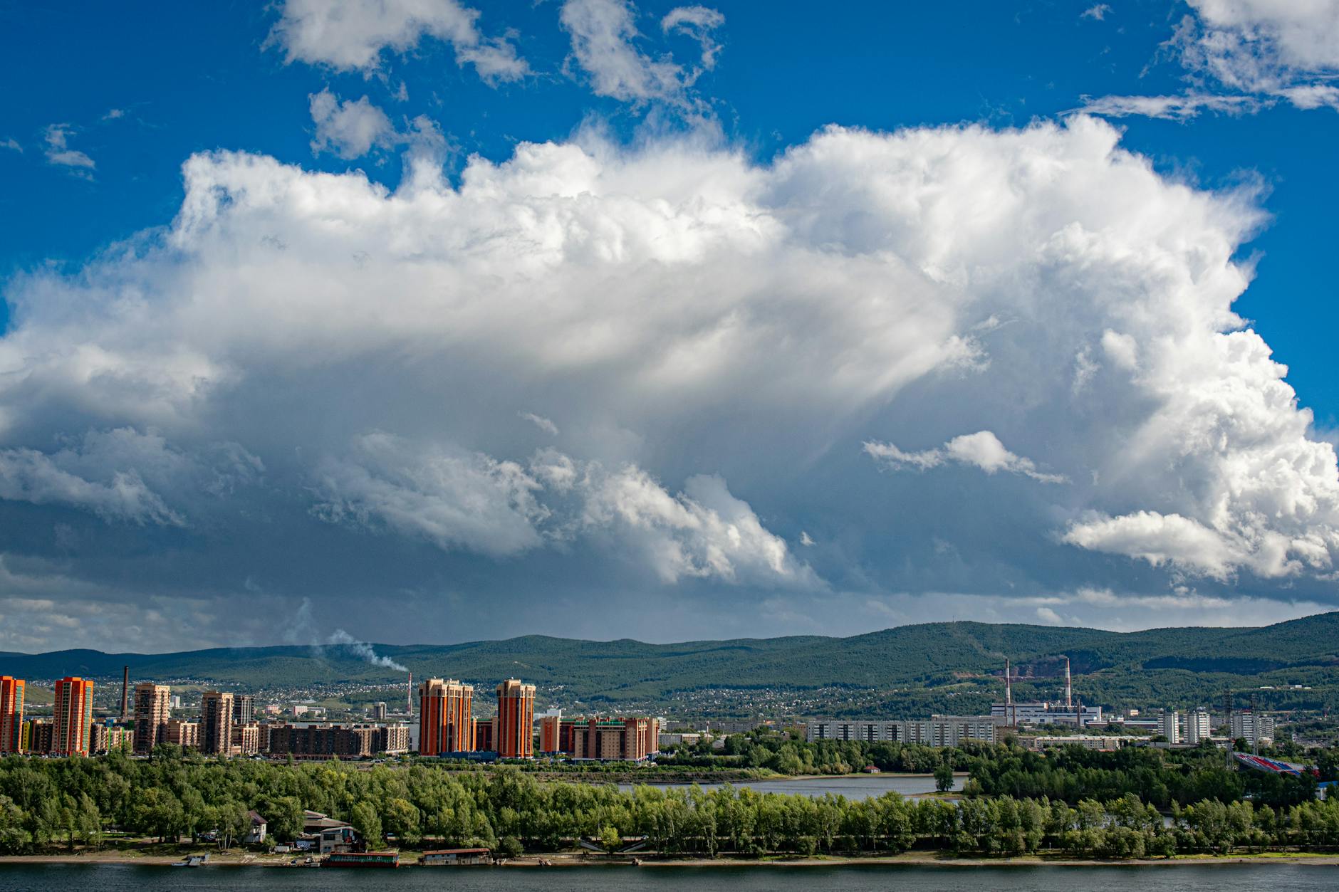 A stunning cityscape with dramatic clouds and bright skies above a vibrant urban area.