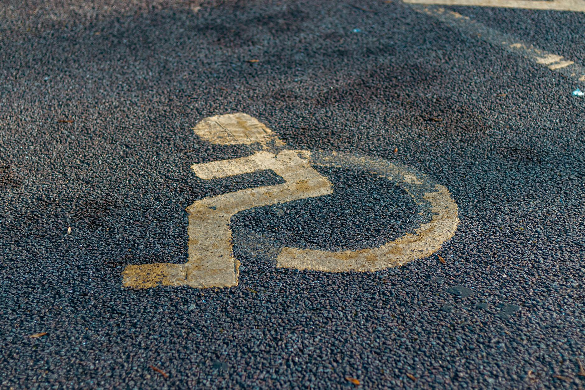 Close-up of a weathered handicap sign painted on a pavement, emphasizing accessibility.