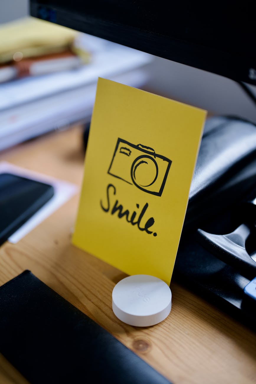 Yellow note with smile message on desk inspires positivity at workspace.