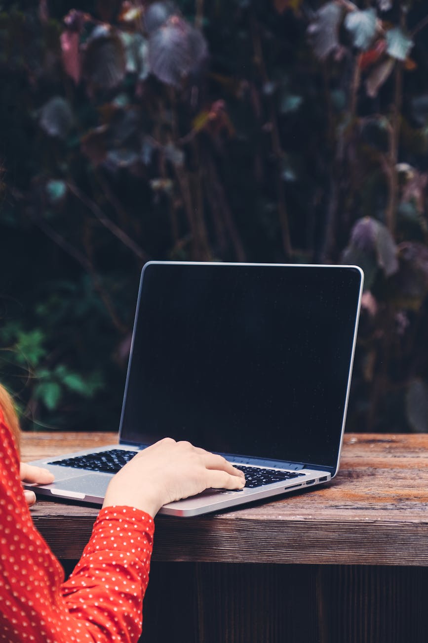 Woman working remotely on a laptop outdoors, showcasing modern digital nomad lifestyle.